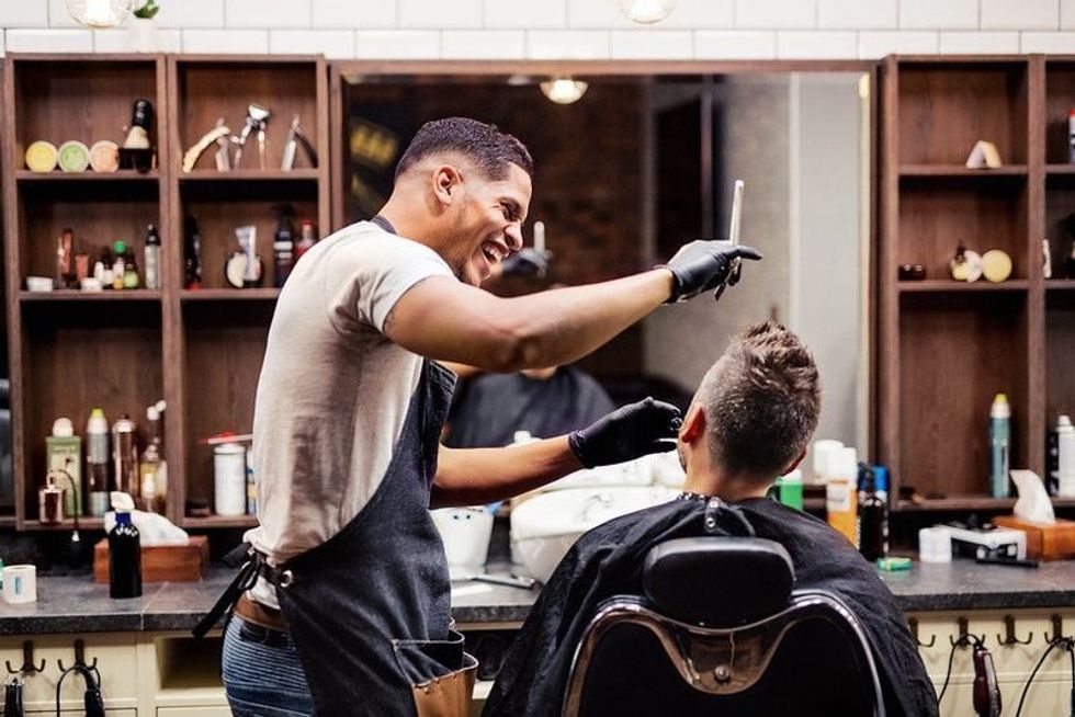 Male client getting groomed by haidresser in a modern barber shop
