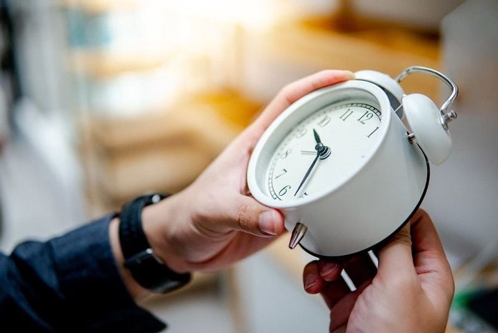 Male hand adjusting or changing the time on white clock