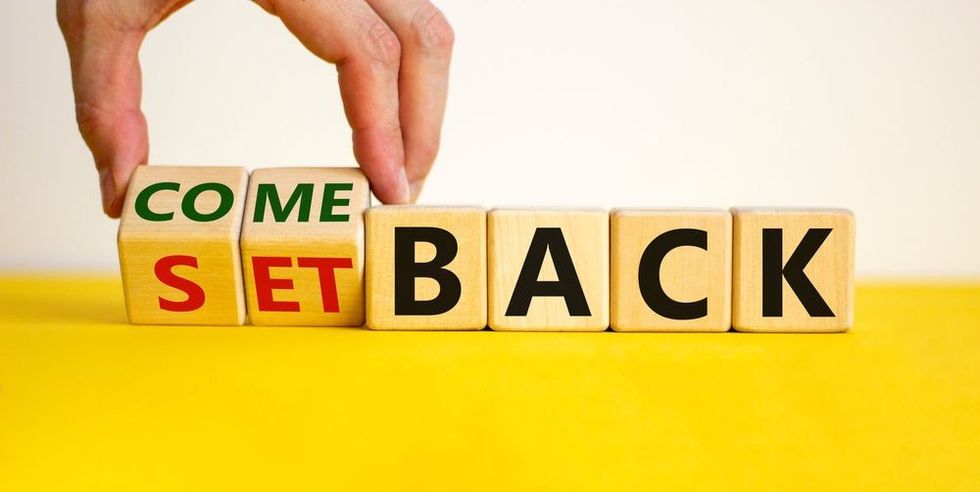 Male hand flips wooden cubes and changes the word 'setback' to 'comeback'.