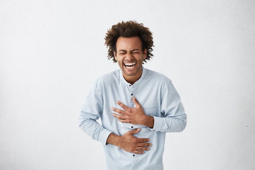 Man holding his hands on stomach while laughing.