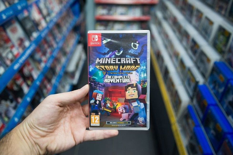 Man holding Minecraft story mode videogame on Nintendo