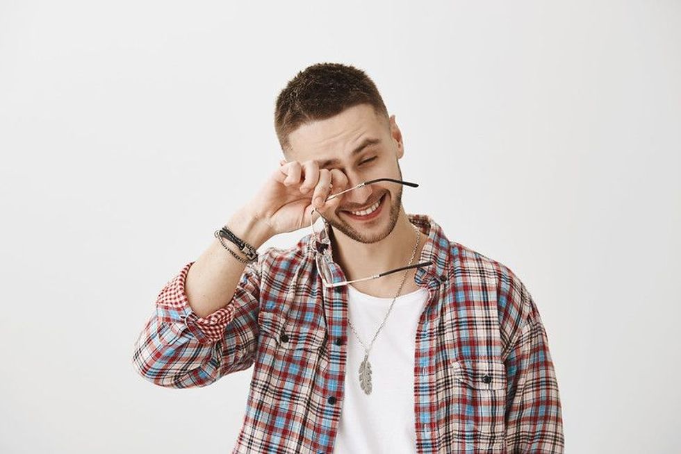 Man laughing while rubbing his eyes