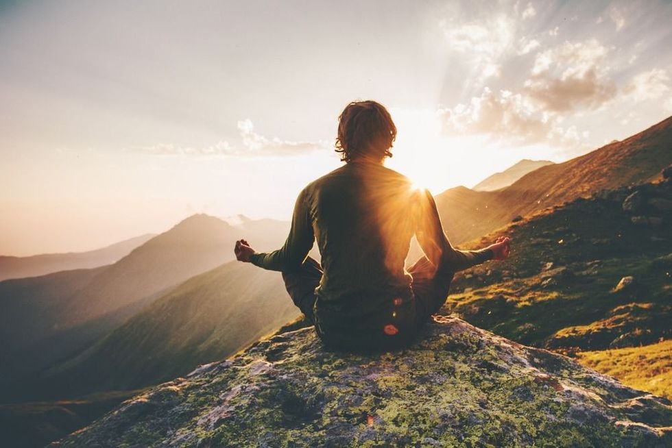 Man meditating yoga at sunset mountains