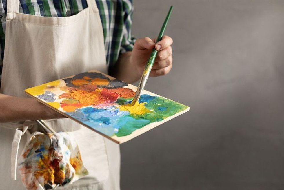 Man painter holding paint palette with paint brush.
