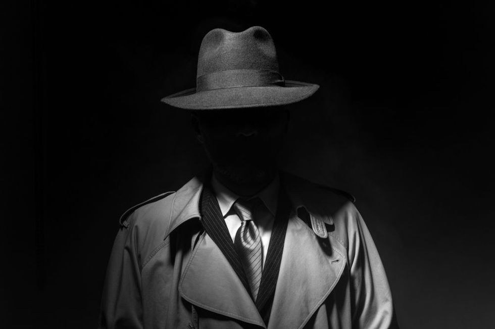 Man posing in the dark with a fedora hat