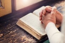 Man praying with the bible open on the table