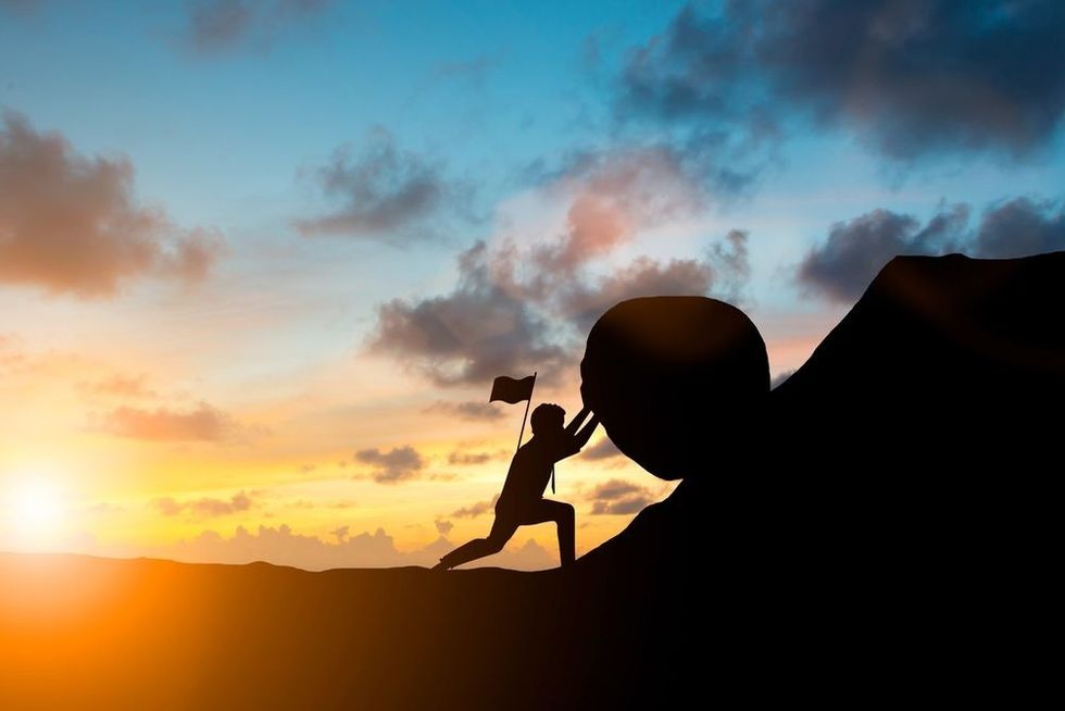 Man pushing a rock with flag