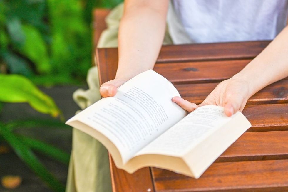 Man reading a book sitting on a bench