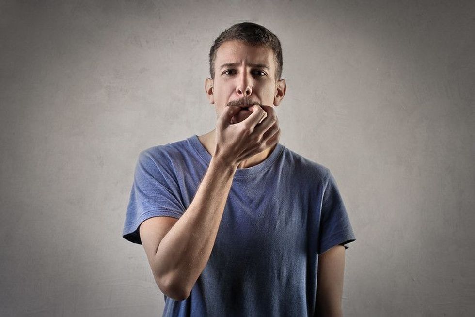Man trying to whistle on isolated grey background.