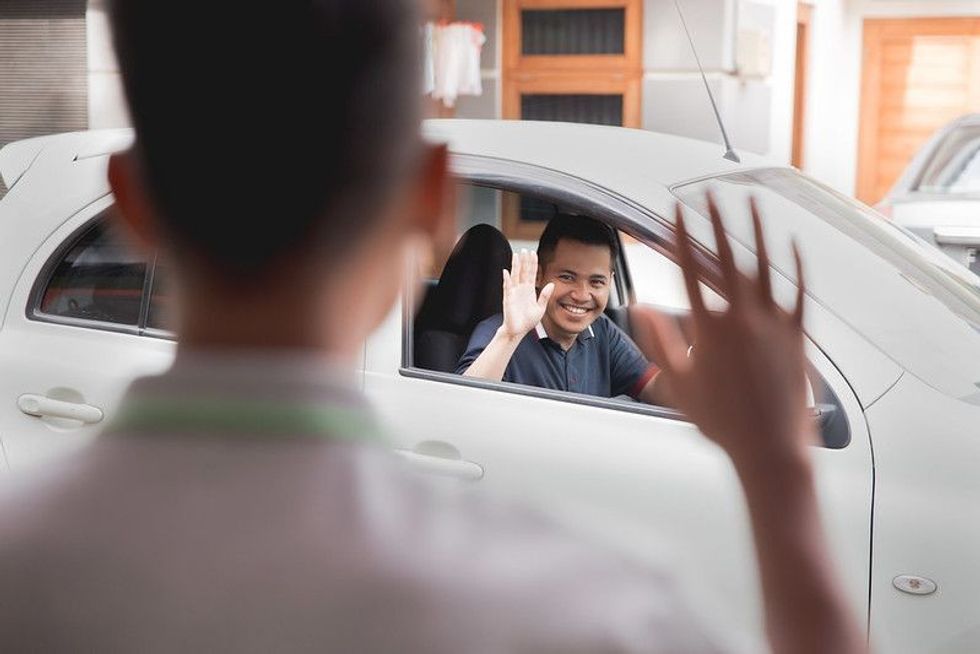 Man wave good bye to his friend while driving a car