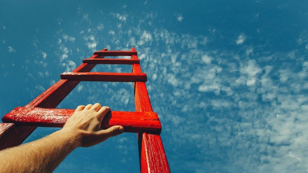  Mans Hand Reaching For Red Ladder Leading To A Blue Sky