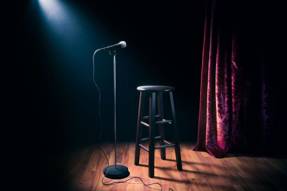 Microphone and stool on a stand up comedy stage with reflectors ray