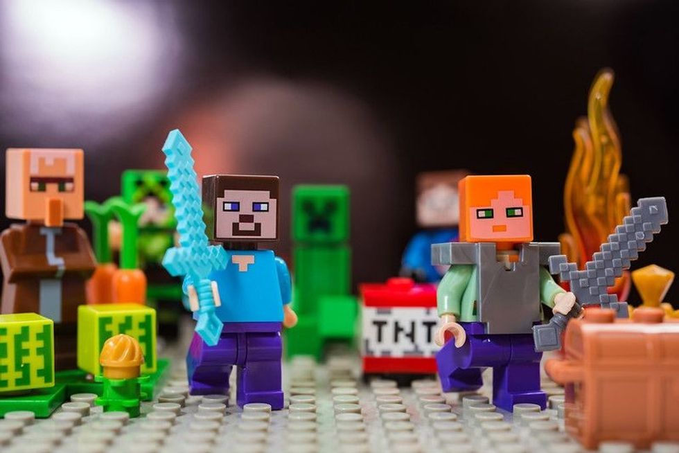 Minifigure Steve with diamond sword and Alex run away from the Creeper. Characters of the game Minecraft.