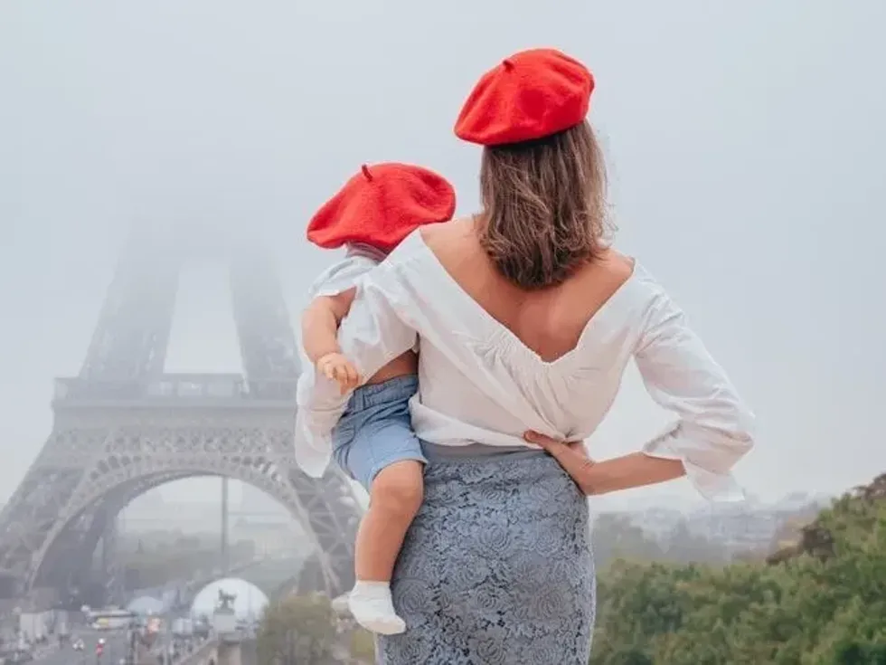 Mom and baby in red berets on the background of the Eiffel tower. 