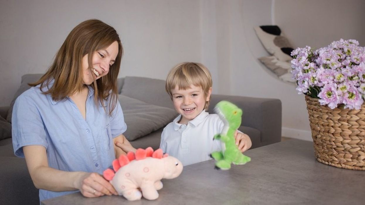 Mom and son have fun role-playing games with plush dinosaur toys
