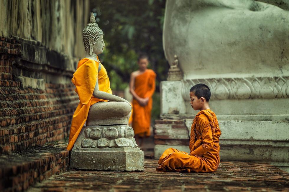 Monk vipassana meditation at front of Buddha statue