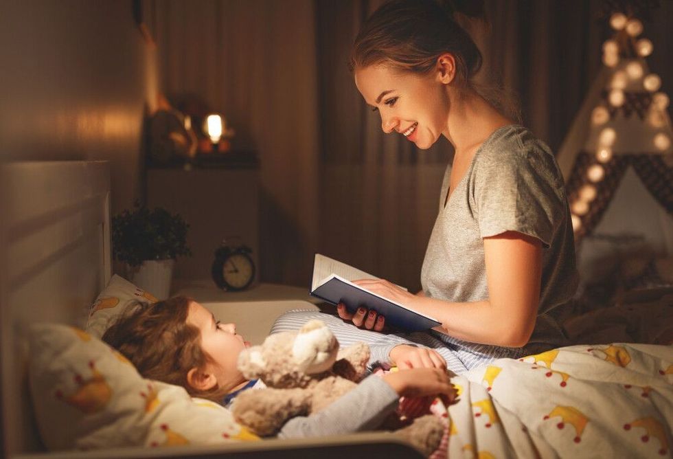 mother and child daughter reading book in bed before going to sleep