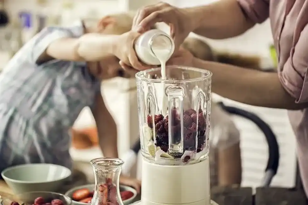 Mother and child making a healthy smoothie together to kick off their day.