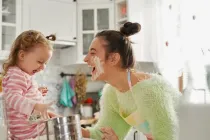 Mother and daughter getting messy in the kitchen making a cake.