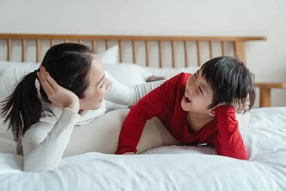 Mother and son lying on the bed laughing at mushroom jokes.