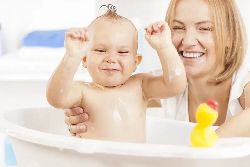 Mother bathing her baby with baby bath support in the tub.