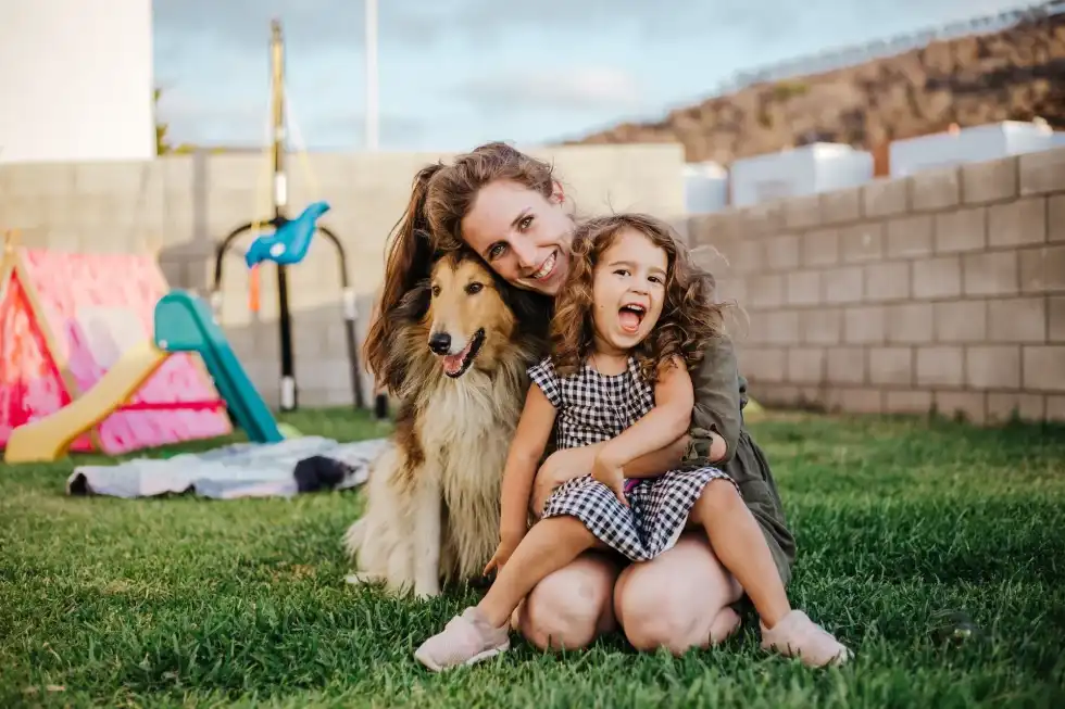 Mother, daughter and their dog playing in their backyard