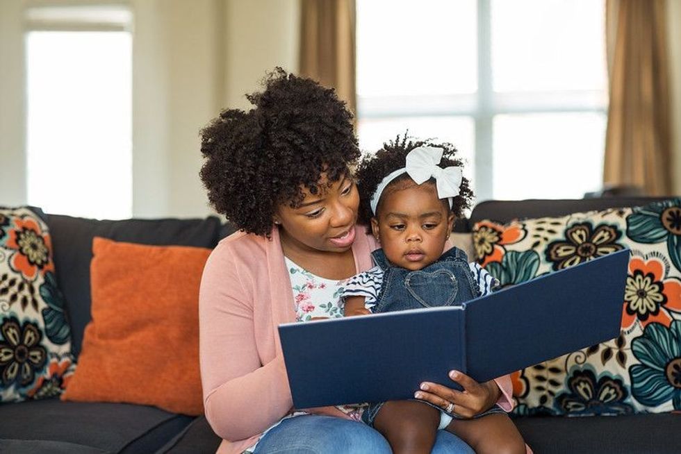 Mother Reading A Book To Her Little Girl.