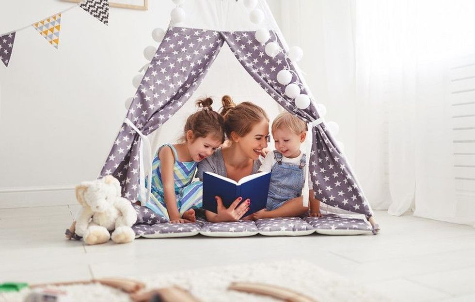 Mother reading children book in a tent.