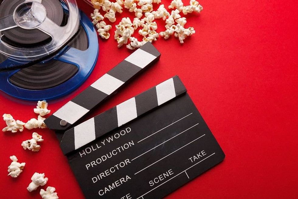 Movie background clapperboard with popcorn and film reel.