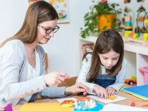 Mum and daughter at table together doing origami crafts.