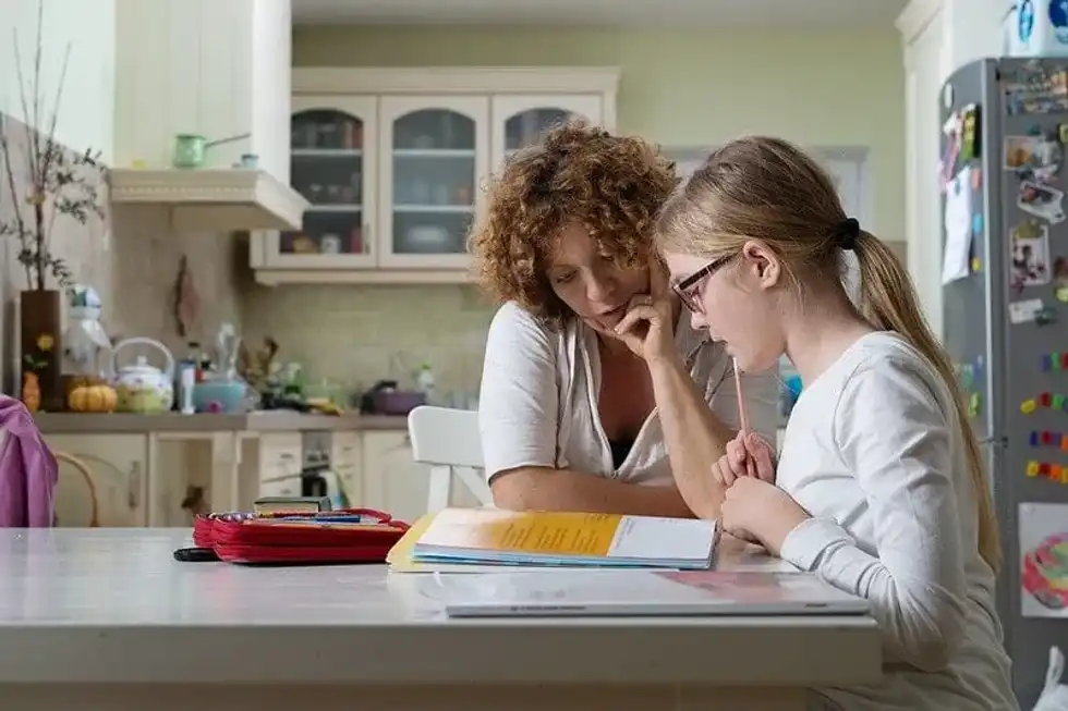 Mum and daughter learning spelling together at the kitchen table.