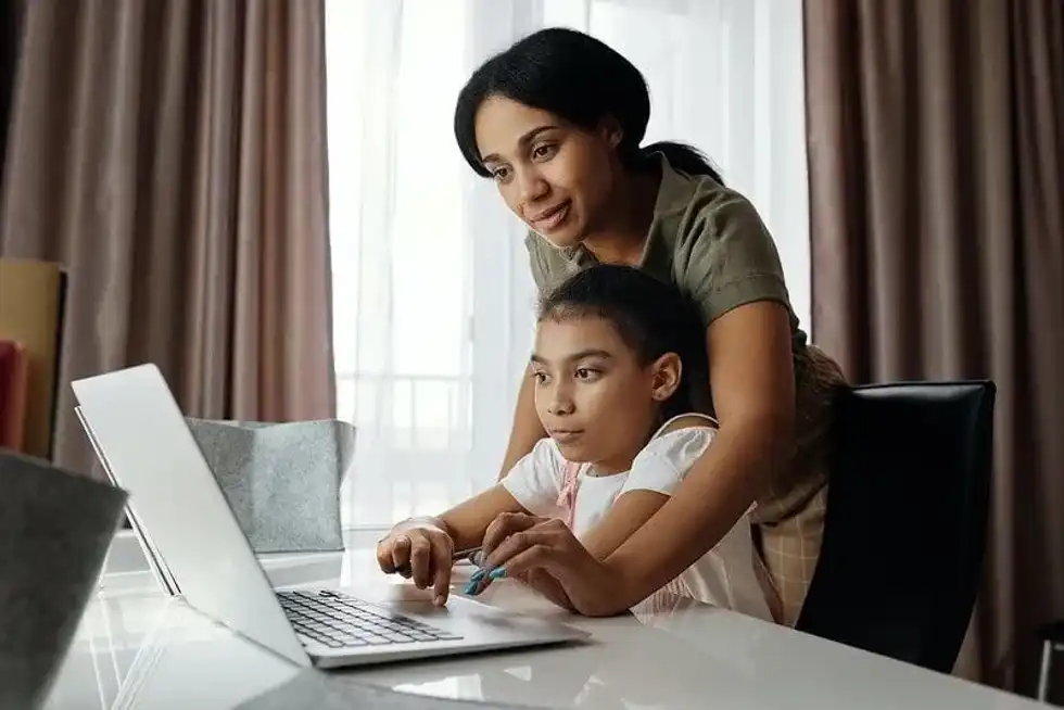 Mum and daughter sat at the desk in front of the laptop, learning about the Stone Age to the Iron Age.
