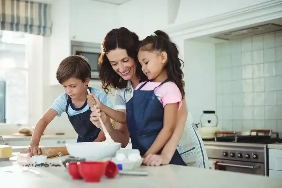 Mum and her two children in the kitchen baking a book cake.