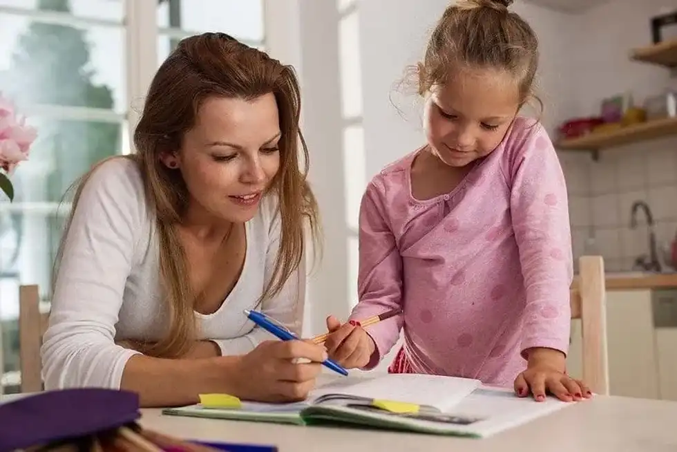 Mum sat at the table with her daughter helping her learn colons and semicolons.