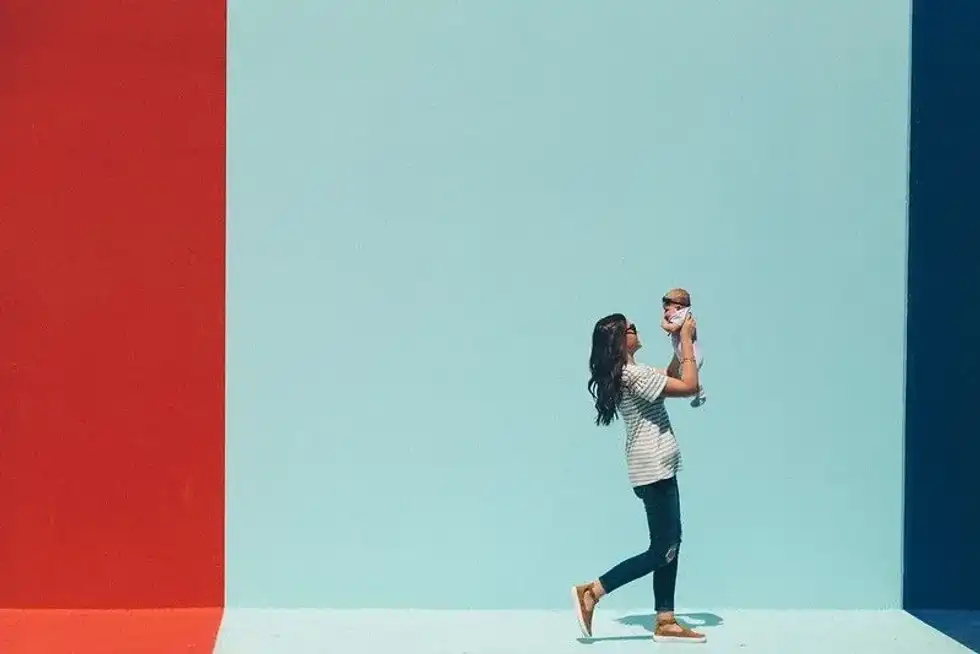New mum walking along holding up her baby in her arms.