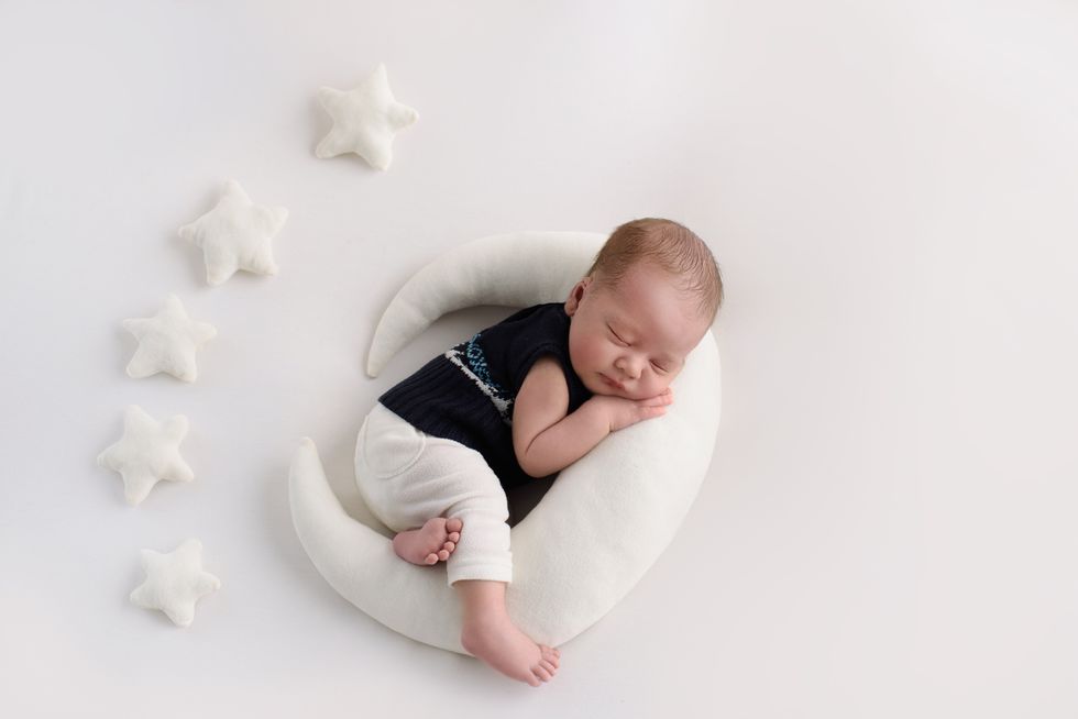 Newborn baby boy sleeping on white moon shaped bed