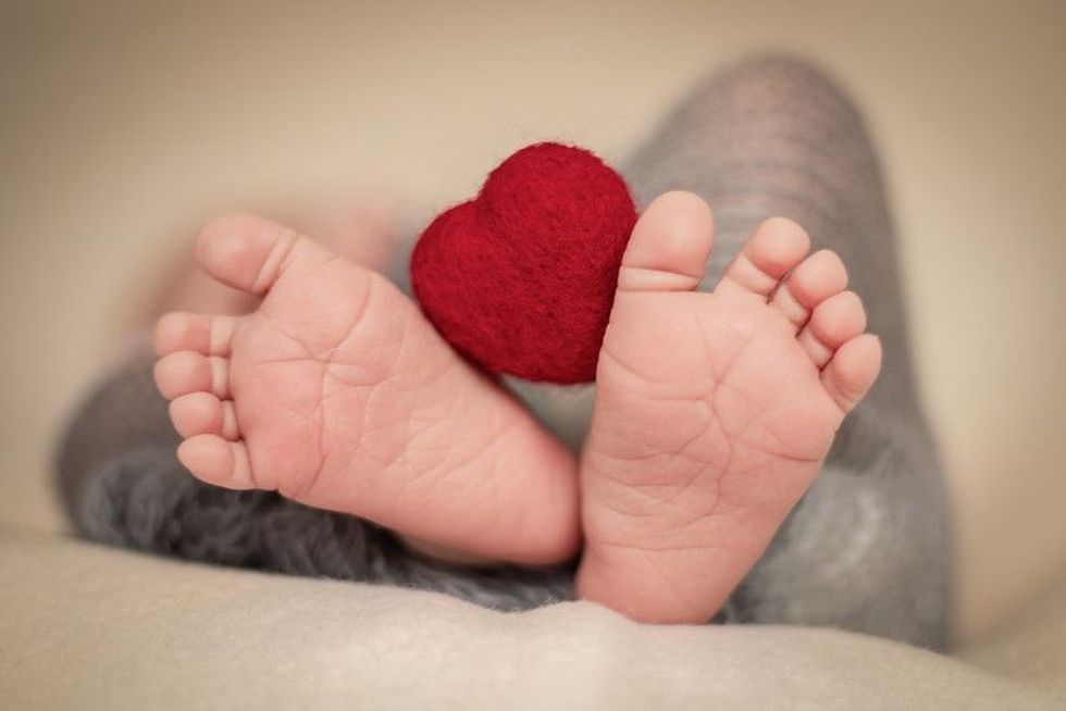 Newborn baby feet with red heart