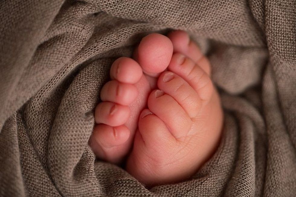 Newborn baby feet wrapped in brown blanket