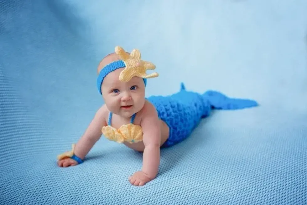 Newborn baby girl in a mermaid costume on a blue background