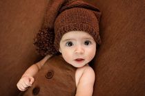 Newborn baby girl wearing warm brown clothes staring at the camera