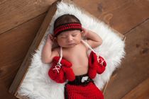 Newborn baby wearing boxing shorts and gloves.