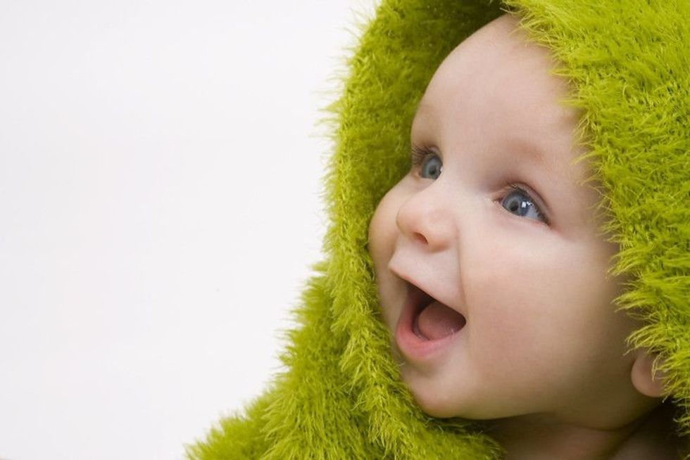 Newborn baby wearing green blanket.