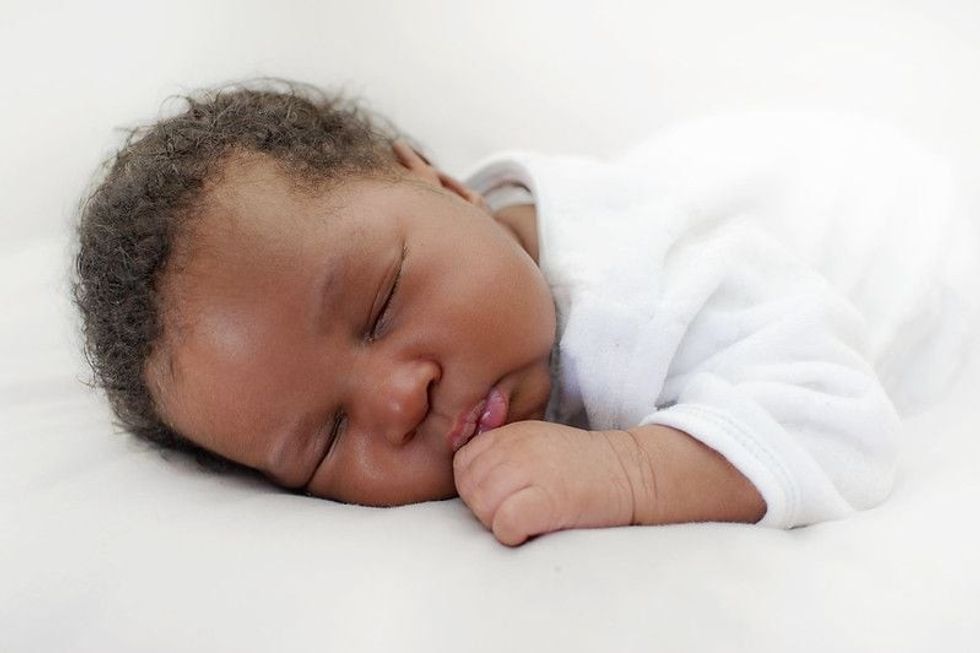 Newborn baby with curly hair sleeping.