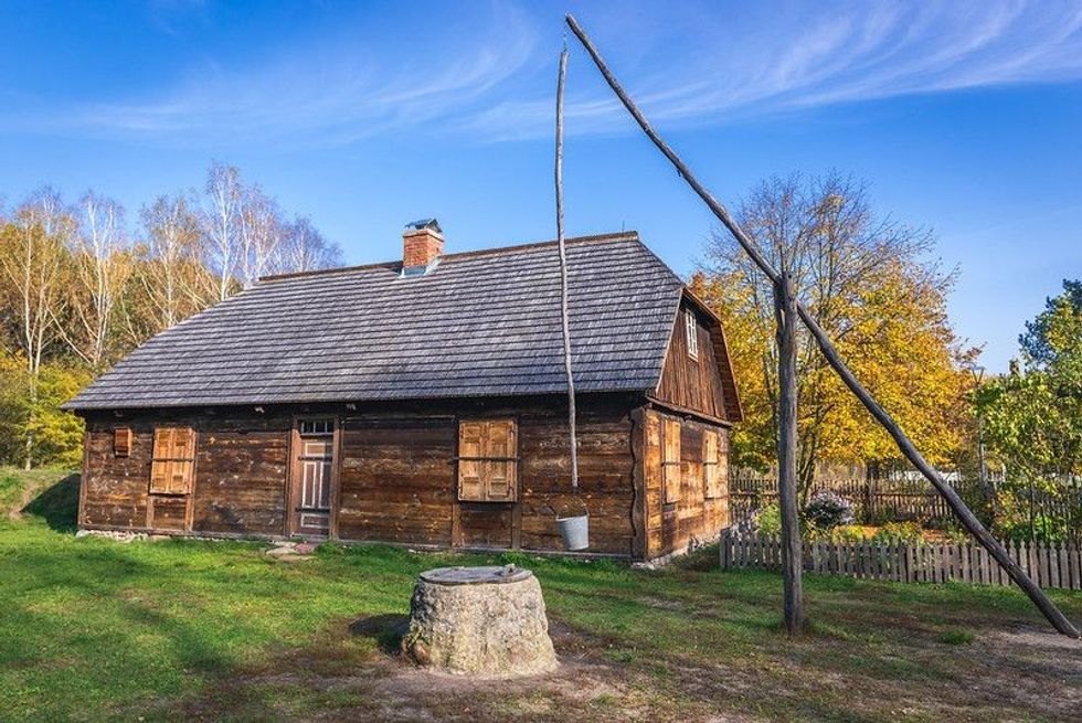 Old wooden traditional house and well sweep in heritage park of Kampinos Forest in Poland