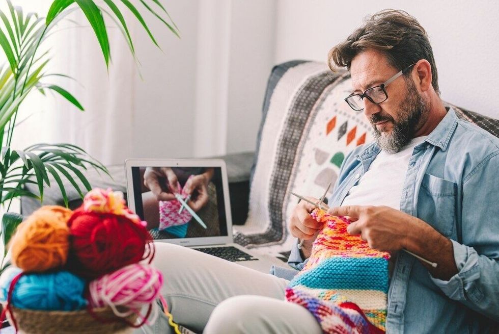 One adult man at home follow online knit tutorial to relax and enjoy resting home leisure activity sitting on the sofa