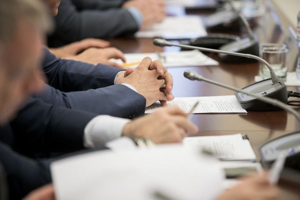 One of politician sitting by table with his hands