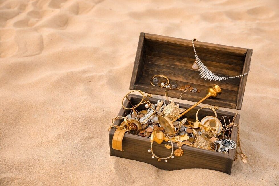 Open wooden treasure chest on sand