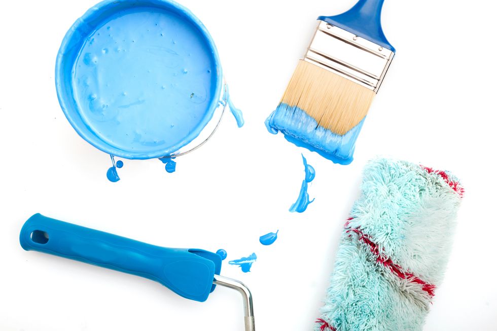 Paint roller and paintbrush on a white backdrop.
