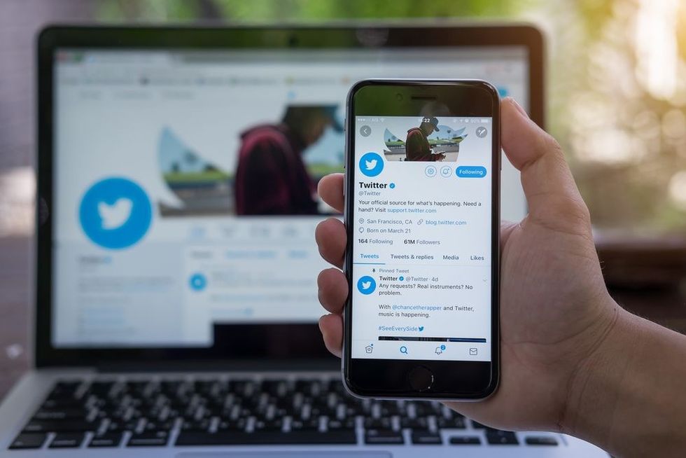 Person holding a brand new Apple iPhone with Twitter logo on the screen. Twitter is a social media online service for microblogging and networking communication.