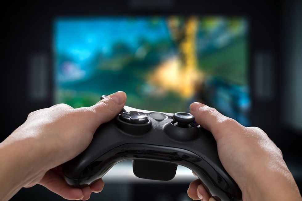 Person playing on the video game console on TV by holding hands game pad.
